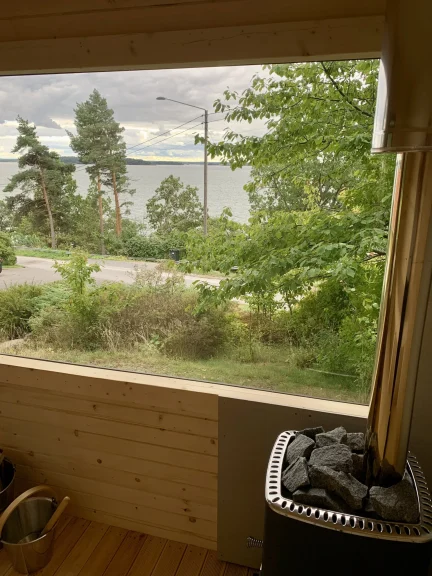 Intérieur d’un sauna en L en bois naturel, avec deux niveaux de banquettes et parois lambrissées