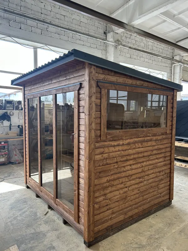 Sauna box en bois naturel, angle avant avec double porte vitrée et fenêtre latérale.