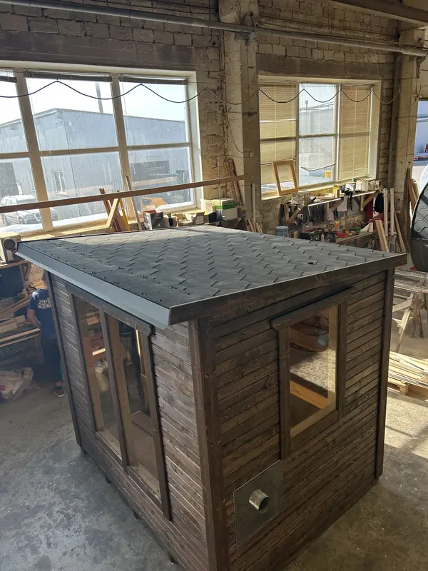 Toiture et mur de sauna en angle, bardage ThermoWood foncé, vue plongeante en atelier.