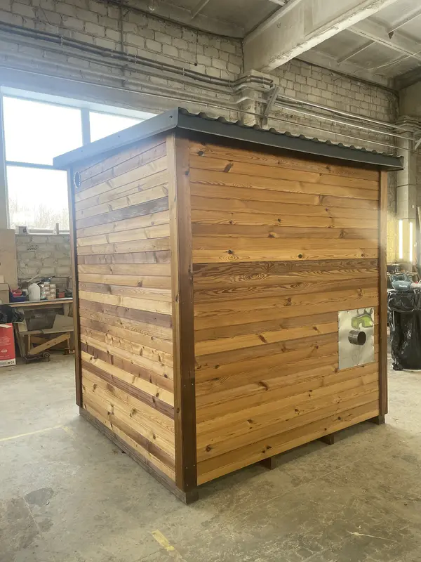Sauna modulable en bois naturel, vue latérale sur le pignon, bardage à lames horizontales et petit aérateur rond