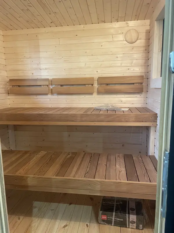 Intérieur clair de sauna modulaire avec banc en bois et petite fenêtre murale