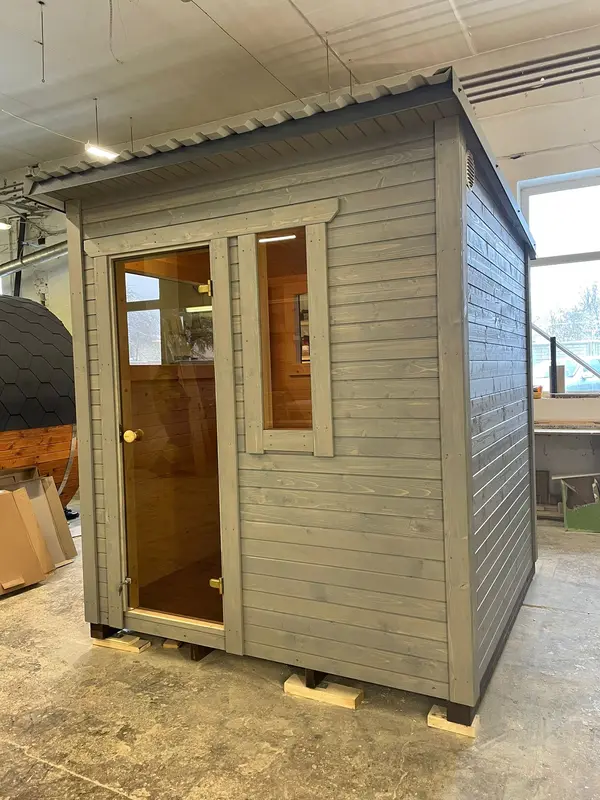 Sauna ThermoWood extérieur peint en noir avec deux larges panneaux vitrés et toit en pente