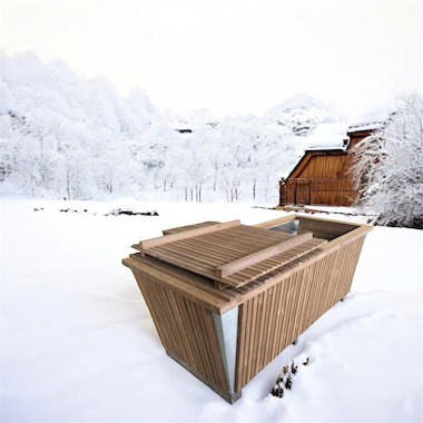 Bain froide en bois encastré dans un caisson, entouré de neige