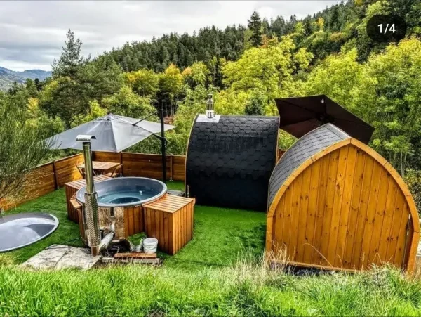 Un cadre idyllique en pleine nature avec un bain à bois et une cabane en forme de tonneau, parfait pour une expérience nordique de détente. Ce site combine confort moderne et immersion dans la nature, idéal pour se ressourcer.