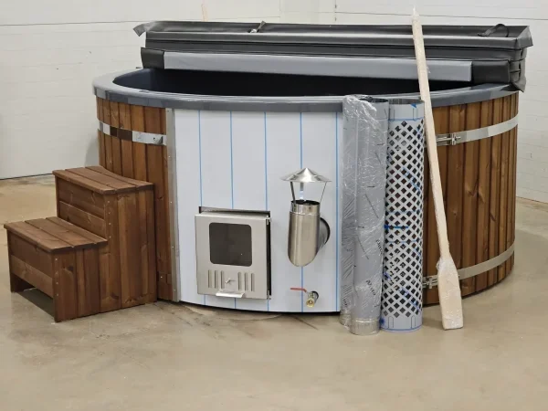 Un jacuzzi extérieur en bois avec un poêle intégré, accompagné d'accessoires tels que des marches en bois et une pagaie, prêt à être installé pour des moments de détente en plein air.